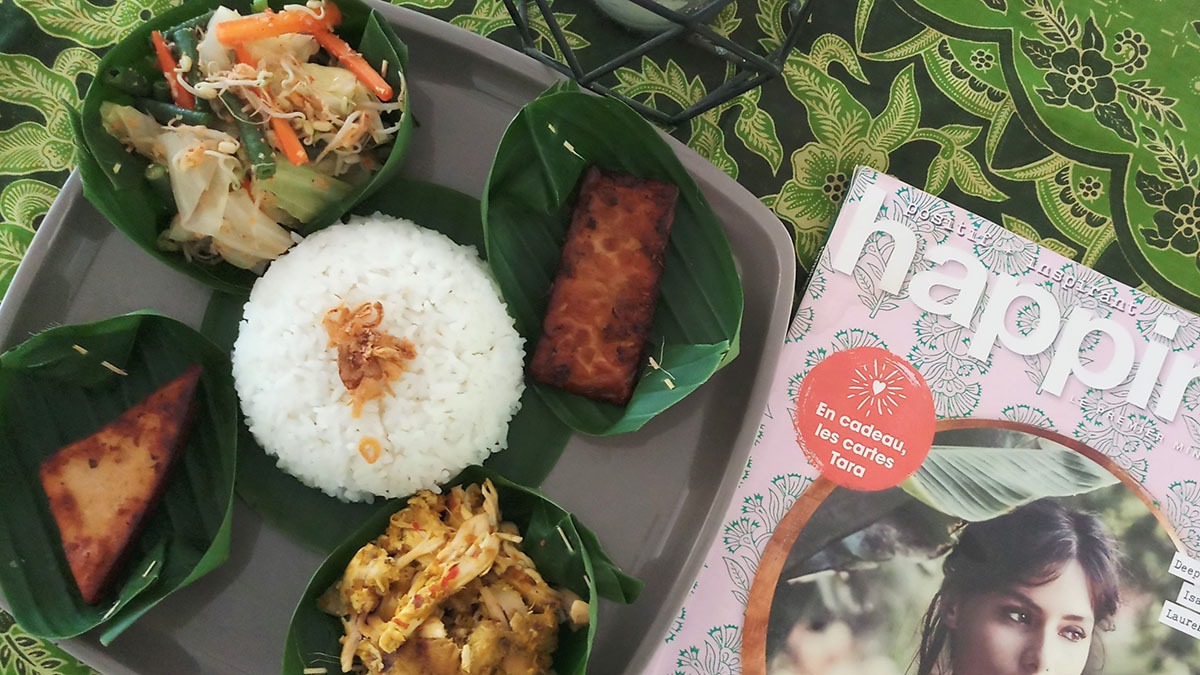 Beautifully plated Indonesian dish with grilled fish, yellow rice, and sambal.